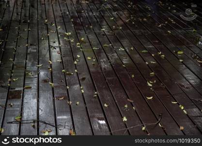 Close-up shots the Old brown rustic wood plank floor and fallen leaves after rain with reflection of lights. Copy space, area for text or lettering.