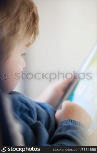 Close up side view of young boy using smart tablet