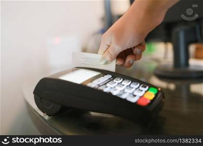 Close up side view on caucasian female hand holding debit or credit payment card using to pay the bill at the store on the terminal payment machine