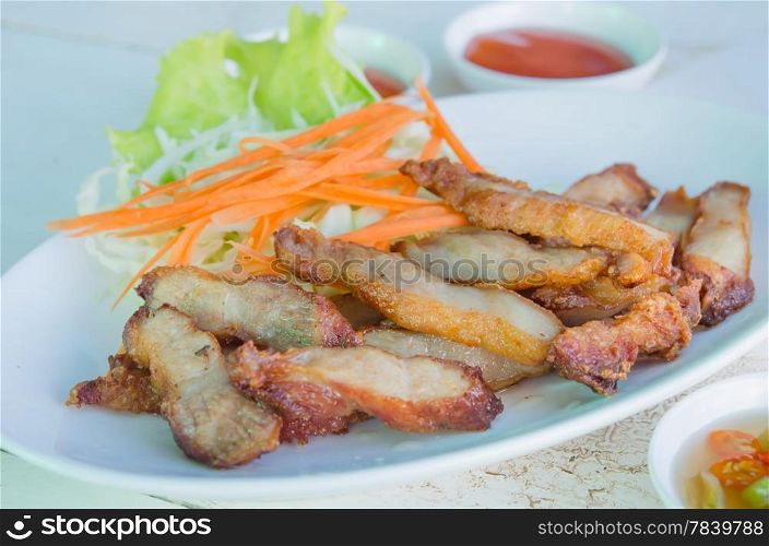 close up slice grilled pork served with fresh vegetable and spicy sauce. grilled pork