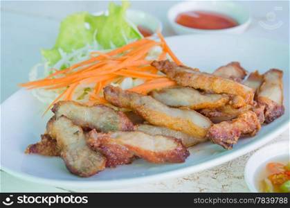 close up slice grilled pork served with fresh vegetable and spicy sauce. grilled pork