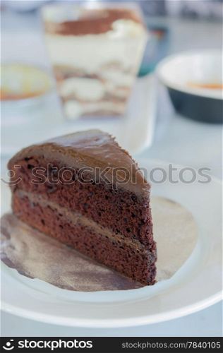 close up slice of chocolate fudge cake on white dish. chocolate cake