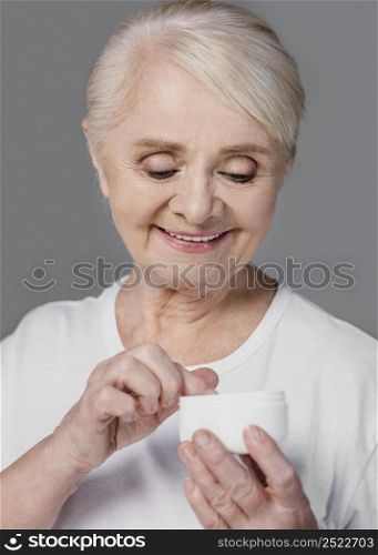 close up smiley woman holding cream container