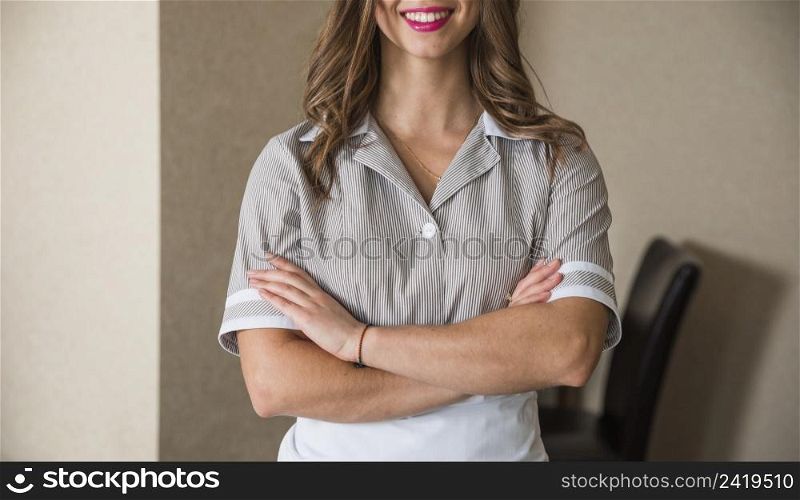 close up smiling chambermaid standing with her arms crossed