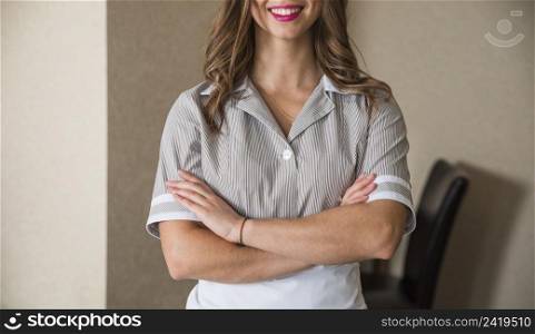 close up smiling chambermaid standing with her arms crossed