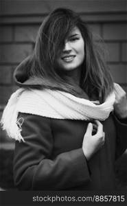 Close up smiling lady in coat with scarf monochrome portrait picture. Closeup side view photography with brick wall on background. High quality photo for ads, travel blog, magazine, article. Close up smiling lady in coat with scarf monochrome portrait picture