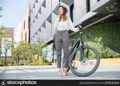 Close up smiling woman wearing helmet exercise outdoors with bicycle on street, Asian young businesswoman putting biking helmet for safety prepared cyclists around building go to work, Bike commuting