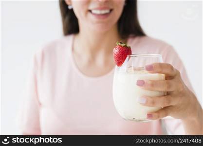 close up smiling young woman holding yogurt glass with strawberry