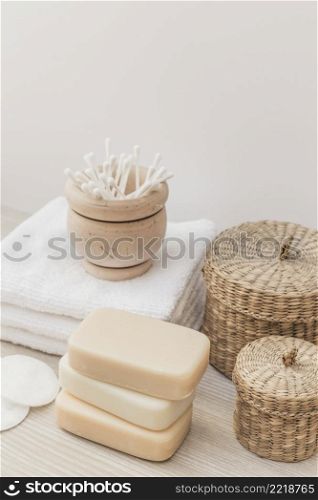 close up soaps sponge cotton swab towel wicker basket wooden surface