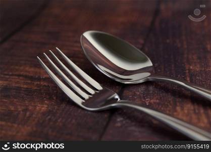 Close up Sparkle stainless fork and spoon placed on the wooden table with rustic style, Empty space for insert text