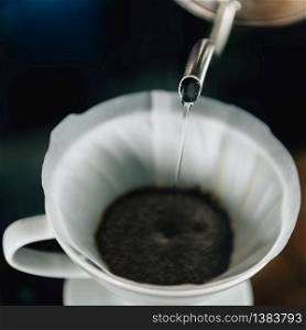 Close up square image of pouring boiling water from kettle to ceramic Drip coffee maker.