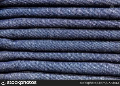 Close up stack of blue denim jeans on display in a clothes shop or store