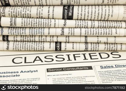 close up stack of fake newspapers, focus on classifieds word