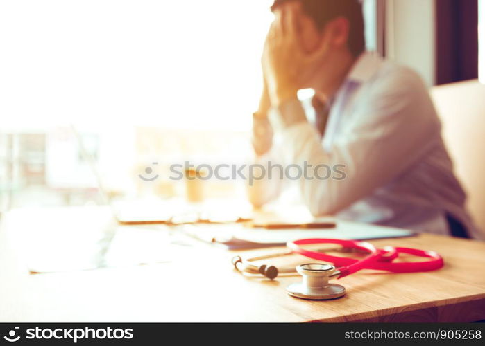 Close up stethoscope and asian doctor sitting with laptop with stress headache.