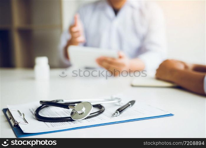 Close up stethoscope and doctor talking the patient at clinic while using the tablet explaining the patient condition and the treatment result.