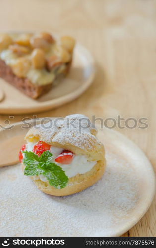 close up strawberry Choux Cream and macadamia cake on wooden dish. strawberry Choux Cream