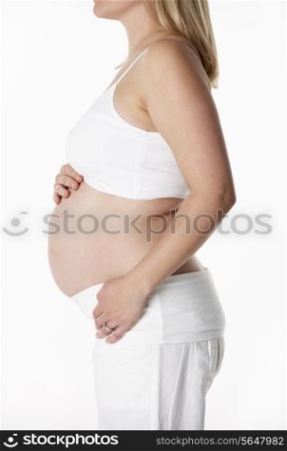 Close Up Studio Portrait Of 5 months Pregnant Woman Wearing White