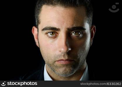 Close up studio portrait of a serious man on black background