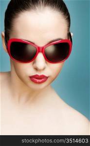close up studio portrait of young beautiful woman wearing red sunglasses