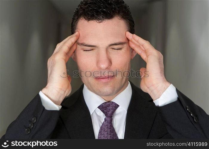 Close up studio shot of a stressed businessman holding his head in pain