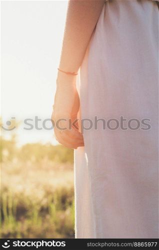 Close up sunlight glare falling on female wrist with red thread concept photo. Back view photography with blurred background. High quality picture for wallpaper, travel blog, magazine, article. Close up sunlight glare falling on female wrist with red thread concept photo