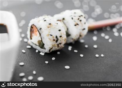 close up sushi roll with sesame seeds uncooked rice black textured background