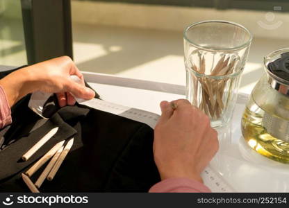 close up the hand of tailor woman taking measure the pattern on the black cloth