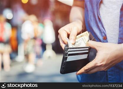 close up the tourist holding an wallet in the hands of an man take money out of pocket of pocket in front of the shop store. money to pay shopping purchase Sell or Payment. expenses finance concept.