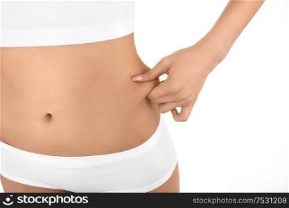 Close up the woman pinches fat on the waist, isolated