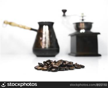 Close-up to coffee beans and a wooden coffee grinder with a cezva on the background