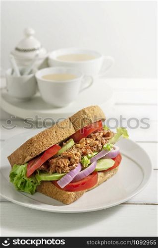 close up toasted sandwich with fish and fresh vegetables on dish. sandwich with fish and fresh vegetables on dish