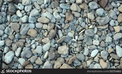 Close-up top view of man taking and throwing stones on the beach as if searching something