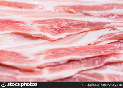 Close up top view pack bacon, pieces raw meat of fresh red pork with white fat slices are sliced into thin strips stacked on top of each other. Closeup pack fresh bacon pork slices