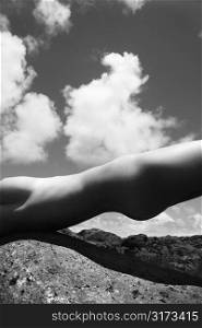 Close up torso of young Caucasian nude woman partially holding self up on rocky Maui coast.