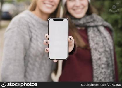 close up two smiling women holding phone hands
