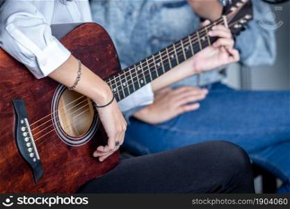 Close up Two women fingers holding mediator with a Guitar recording a song in recording studio