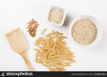 close up uncooked fusilli pasta rice crushed cinnamon with spatula white background
