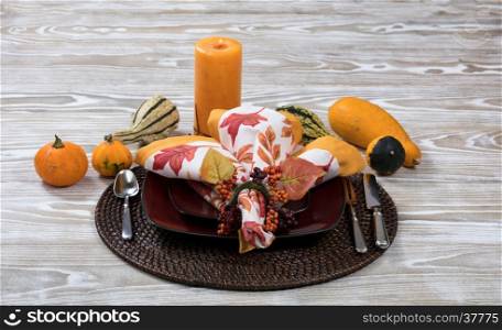 Close up view of a festive autumn dinner setting with real gourd decorations and candle in background