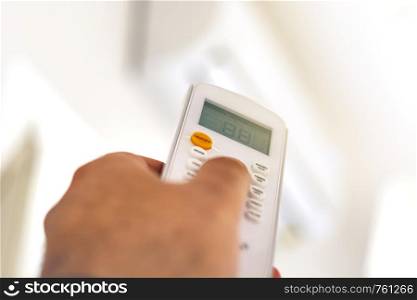close-up view of a hand adjusting the air conditioning temperature using the remote control. Home comfort. Air conditioning and appliances