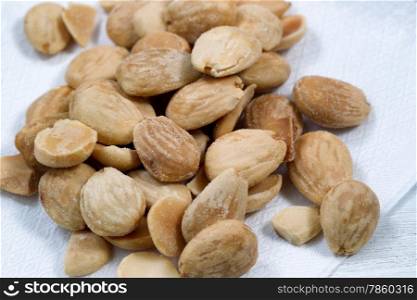 Close up view of a pile of salted almonds on white cloth napkin. Focus front middle of pile.