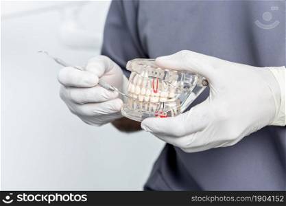 Close up view of a transparent dental mould in the hands of a dentist using white gloves. Close up view of the hands of a dentist holding a dental mould