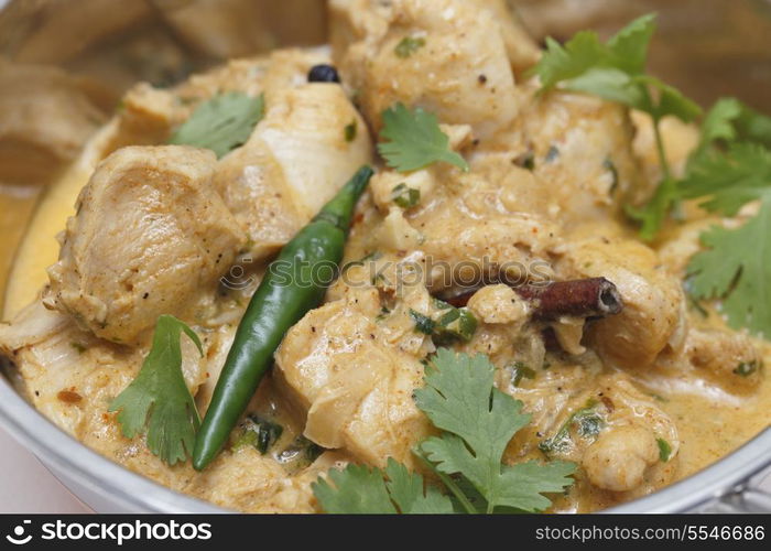 close-up view of balti chicken pasanda curry served, garnished with coriander leaves and a red chilli in and Indian kadai serving bowl. This curry is made with yoghurt , cream and chopped coriander as well as the usual spices, to give a fairly mild and creamy flavour.