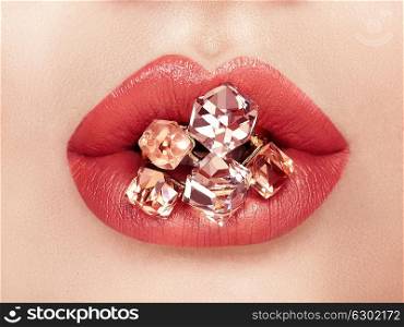 Close up view of Beautiful Woman Lips with Red Lipstick. Open Mouth with white Teeth. Cosmetology, drugstore or Fashion Makeup Concept. Jewelry dyeing gems