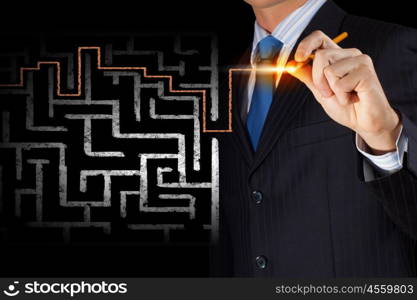 Close up view of businessman drawing way in labyrinth. Searching way out