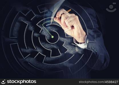 Close up view of businessman drawing way in labyrinth. Searching way out