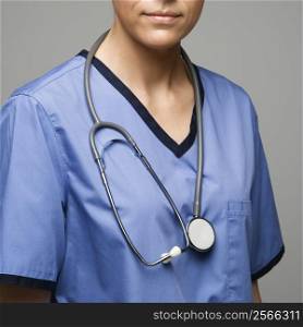Close-up view of Caucasian woman doctor wearing scrubs with stethoscope around neck.