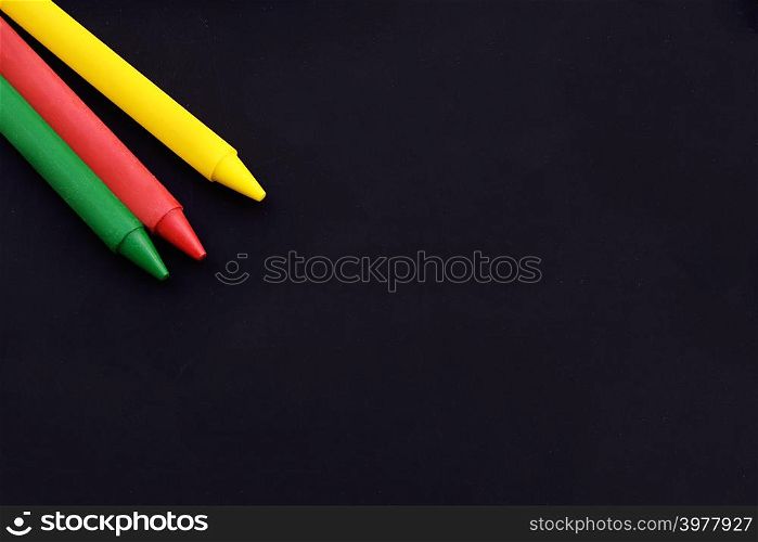 Close up view of colorful wax crayons with copy space on black background.