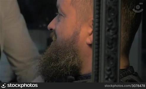 Close up view of female barber taking cares of lush beard of white olded man