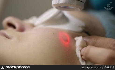 Close-up view of female cosmetitian providing a laser facial treatment for a woman in clinic.