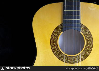 close up view of fretboard and sound hole of guitar on black with space for copy